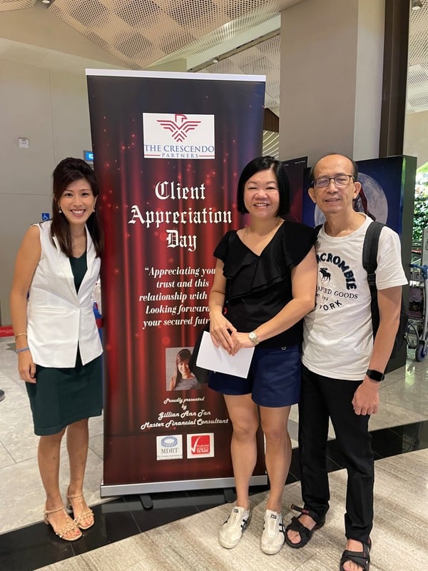 Gillian and two guests beside a Client Appreciation Day banner
